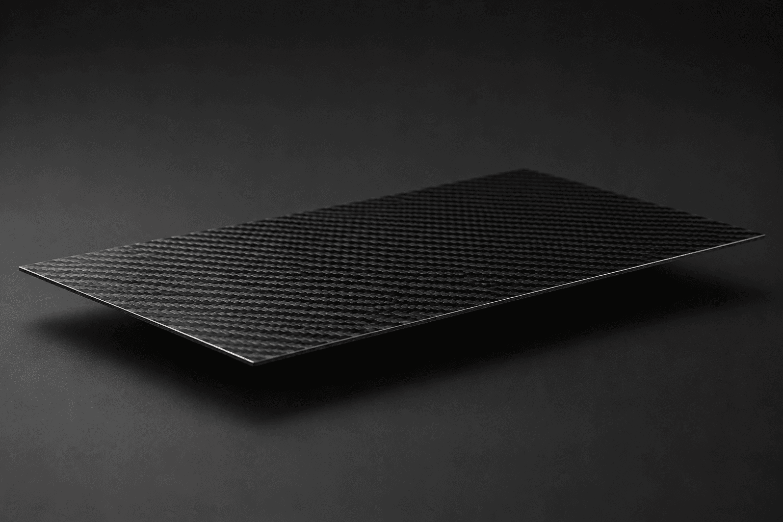 Flat woven carbon fiber sheet on a dark surface